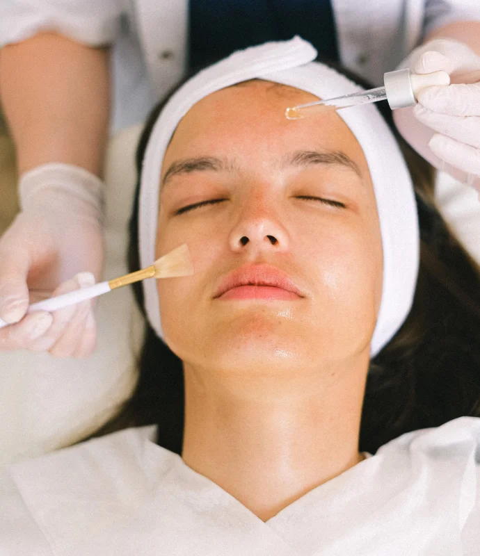 a-woman-receiving-a-facial-treatment-with-the-serum-and-brush-directed-towards-her-face.